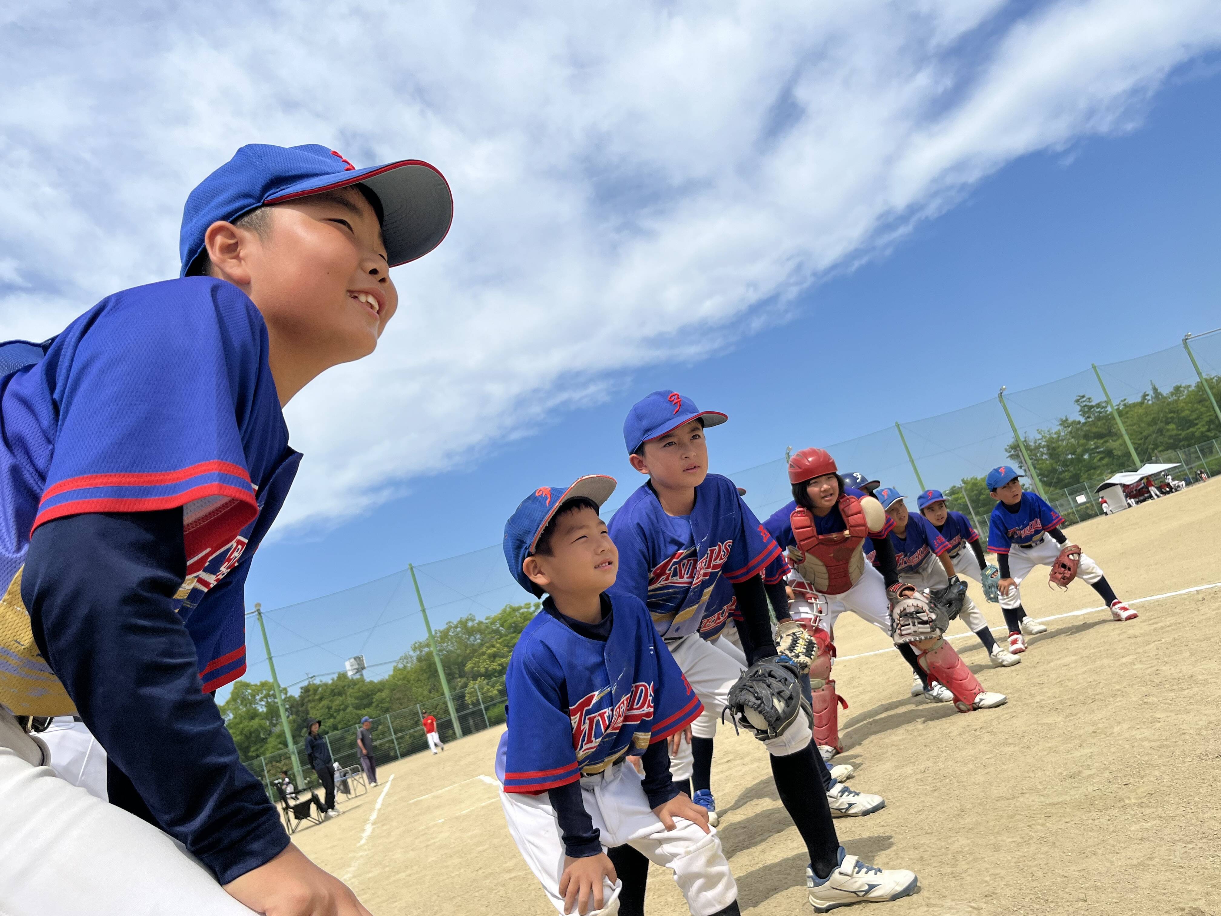 最優秀賞 五福ファイブキッズ ― 青空の下、守備位置に並び笑顔で試合に臨む選手たち（第22回倉敷ケーブルテレビ杯ソフトボール大会フォトコンテスト受賞作品）