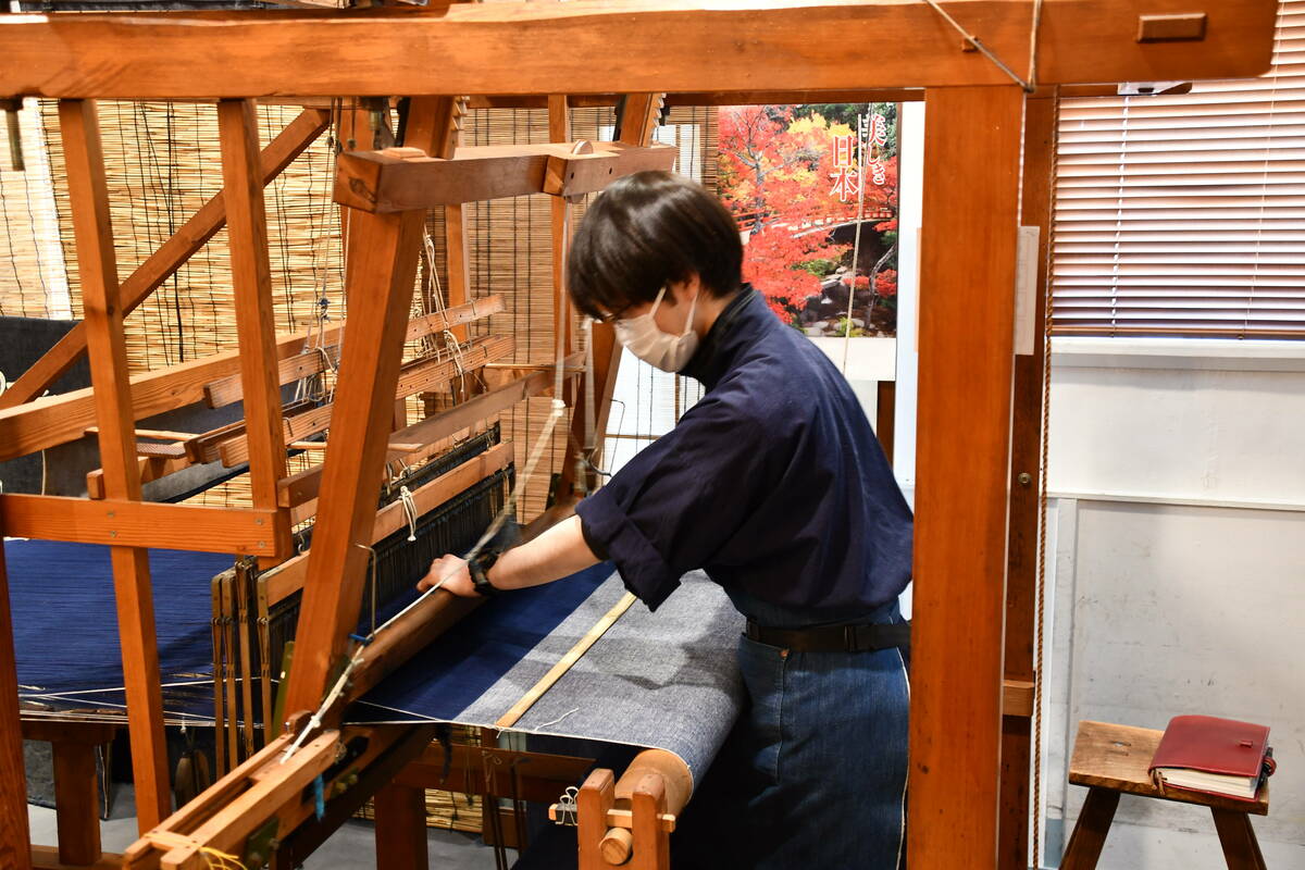 高機(たかばた)で生地を織る職人さんの写真