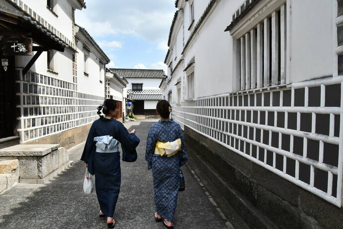 なまこ壁の路地を歩く2人